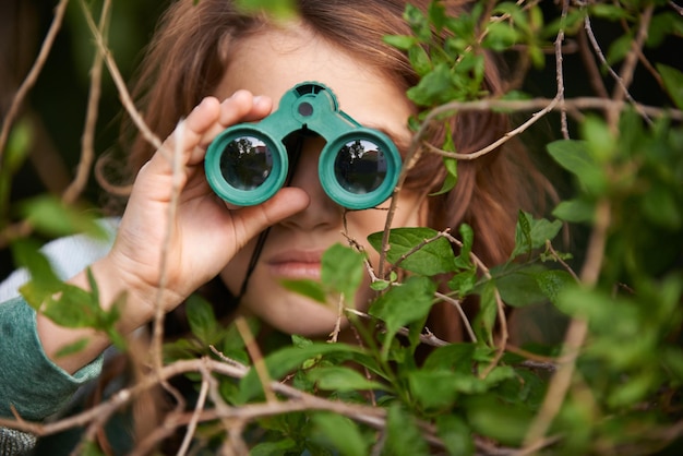 La observación de aves es algo serio Foto de una linda niña mirando a través de un par de binoculares al aire libre