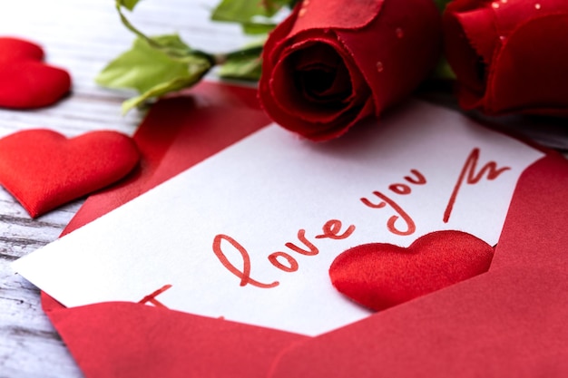 Observe que diz "eu te amo" dentro de um envelope com corações e rosas na mesa de madeira