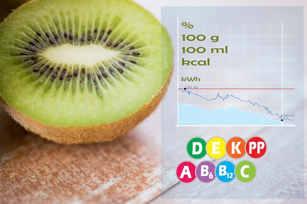 Obst-, Ernährungs-, Lebensmittel- und Objektkonzept - Nahaufnahme einer reifen Kiwi-Scheibe auf dem Tisch mit Kalorien- und Vitamintabelle