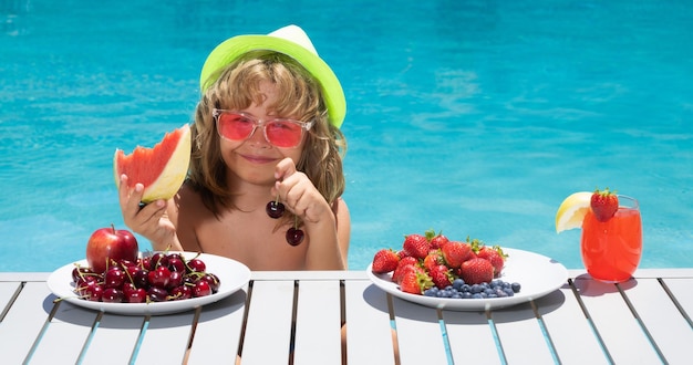 Obst für Kinder Sommercocktail und Obst glückliches Kind, das sich am Sommertag am Pool amüsiert Kinder