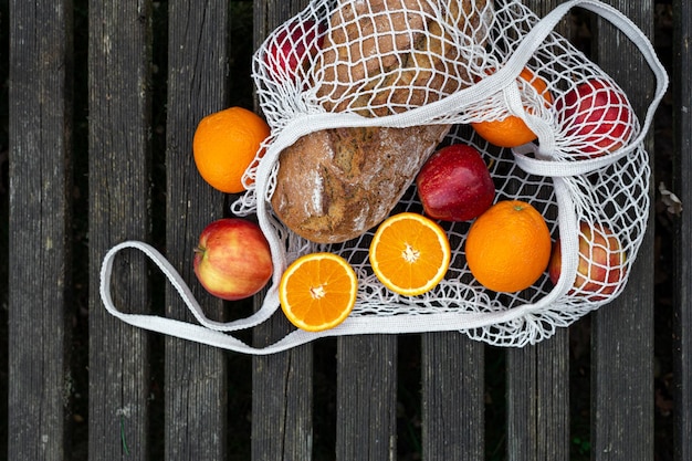 Obst und Brot in einer Einkaufstasche auf Holzhintergrund