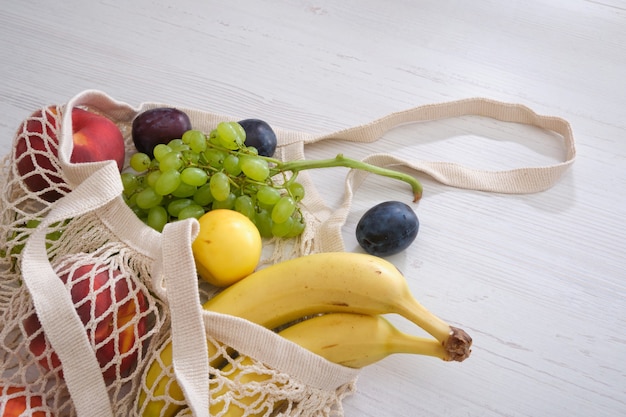 Obst und Gemüse in einem Netzbeutel auf einem hölzernen Hintergrund