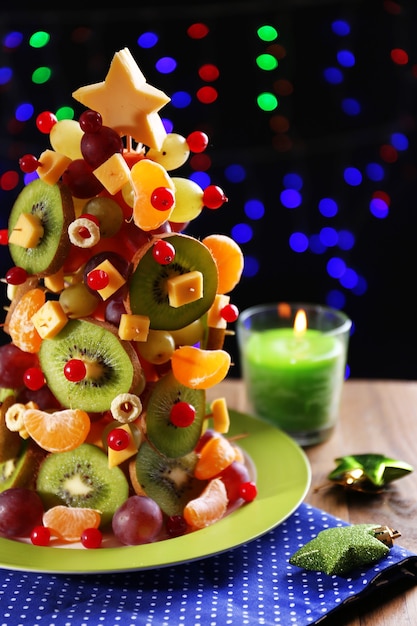 Obst-Weihnachtsbaum auf dem Tisch auf dunklem Hintergrund