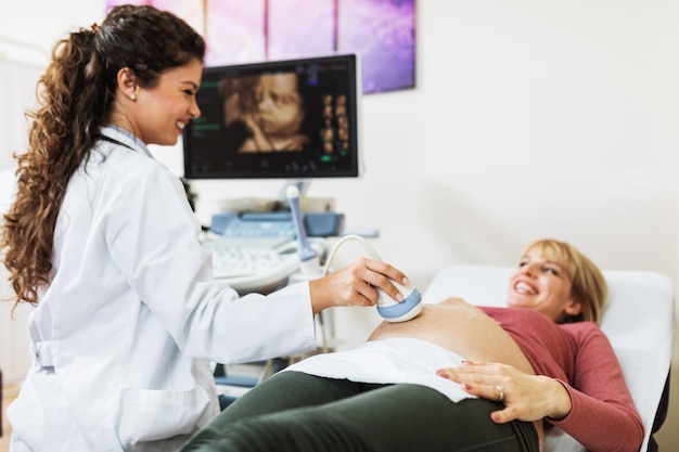 Obstetra examinando el vientre embarazado por ecografía.