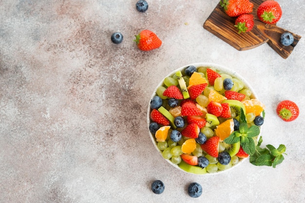 Obstsalat aus Blaubeeren, Erdbeeren, Trauben und Kiwi in einem Teller, Draufsicht, Kopierraum