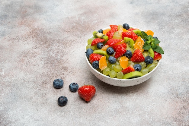 Foto obstsalat aus blaubeeren, erdbeeren, trauben und kiwi in einem teller, eine kopie des raumes