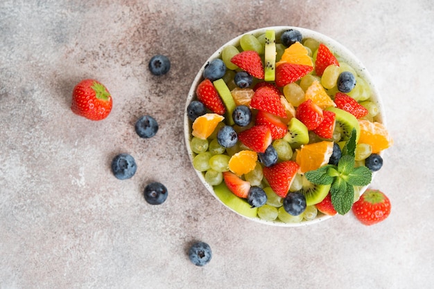Obstsalat aus Blaubeeren, Erdbeeren, Trauben und Kiwi in einem Teller, selektiver Fokus, Draufsicht
