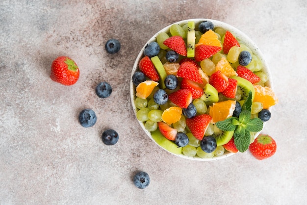 Foto obstsalat aus blaubeeren, erdbeeren, trauben und kiwi in einem teller, selektiver fokus, draufsicht