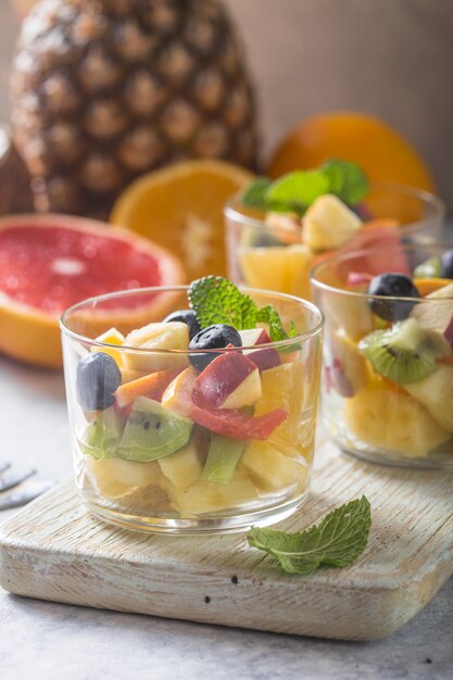 Obstsalat in den Gläsern, frische Sommernahrungsmittel, gesunde organische orange Kiwiblaubeerananaskokosnuss. Ansicht von oben