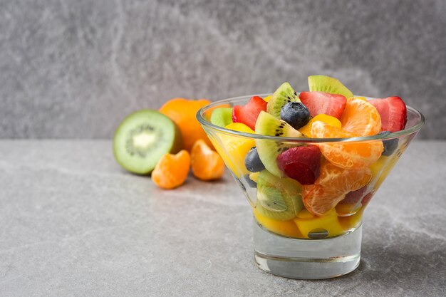 Obstsalat in Kristallschale auf grau mit Kopienraum