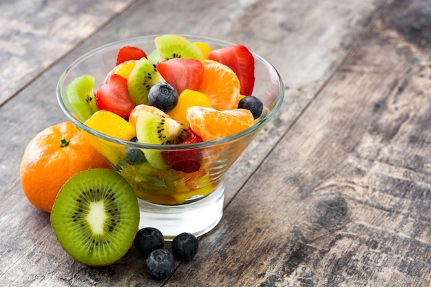 Obstsalat in Kristallschale auf Holztisch mit Kopienraum