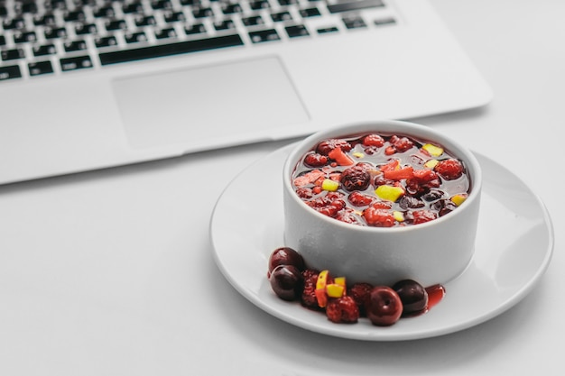 Obstsalat mit Laptop auf Weiß. Gesundes Frühstückskonzept.