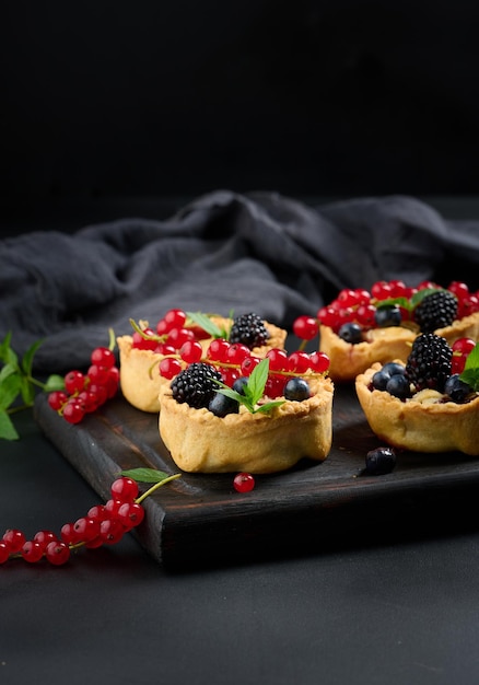 Obsttorte mit roten Johannisbeeren, bestreut mit Puderzucker auf einem schwarzen Tisch