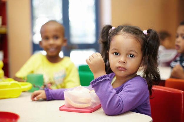 Obtendo energia para as atividades divertidas à frente Crianças em idade pré-escolar na hora do almoço comendo sanduíches