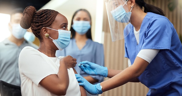 Obtendo sua injeção de reforço Foto recortada de uma jovem empresária atraente recebendo sua vacina cobiçosa de uma enfermeira no escritório