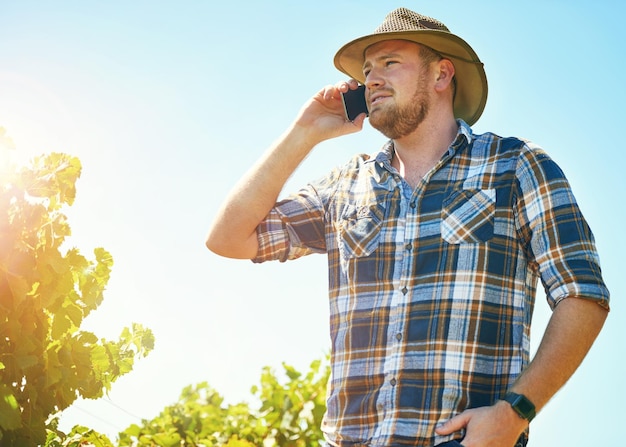 Obteniendo algunos consejos de un compañero agricultor Foto de un agricultor hablando por teléfono mientras está en un viñedo