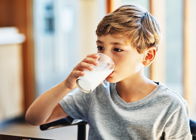 Obteniendo su dosis diaria de calcio Toma de un niño bebiendo un vaso de leche en casa