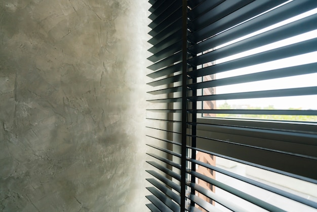 Obturador cego de janela com sombra clara e muro de concreto