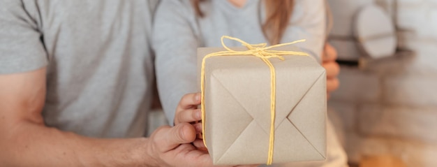 Ocasión especial familiar Primer plano de un paquete de papel atado con un cordón amarillo Padre cariñoso e hija sosteniendo un regalo