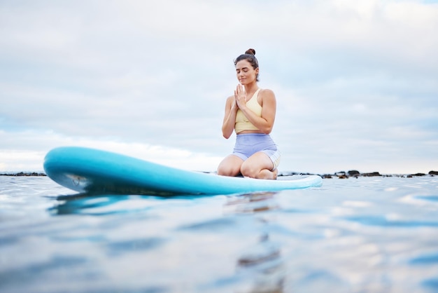 Oceano de meditação de ioga e mulher surfista meditando para saúde, bem-estar, paz ou liberdade na água do mar, oração de pilates e garota zen meditar para aura de fitness de praia ou cura de energia de chakra