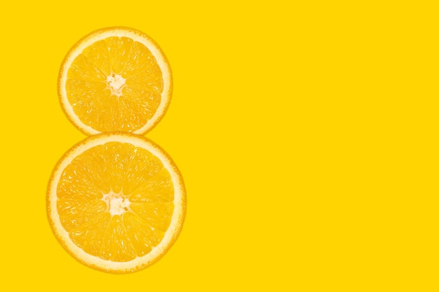 Ocho dígitos: naranja en rodajas, fondo amarillo, copie el espacio. Telón de fondo brillante del día de la mujer 8 de marzo. Fruta fresca y jugosa, fuente de vitamina C.