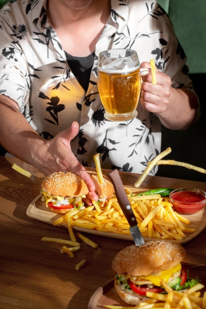 Ocio amistad comida y concepto de comida primer plano de un chico cortando una hamburguesa con la mano en un bar