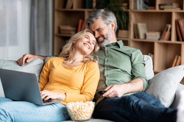 Ocio doméstico Cónyuges románticos de mediana edad viendo películas en una computadora portátil en casa