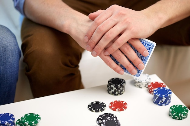 Ocio, juegos, amistad, juegos de azar y entretenimiento: cierre de la mano masculina con cartas y fichas en casa