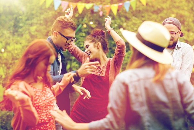 ocio, vacaciones, diversión y gente concepto - amigos felices bailando en la fiesta de verano en el jardín
