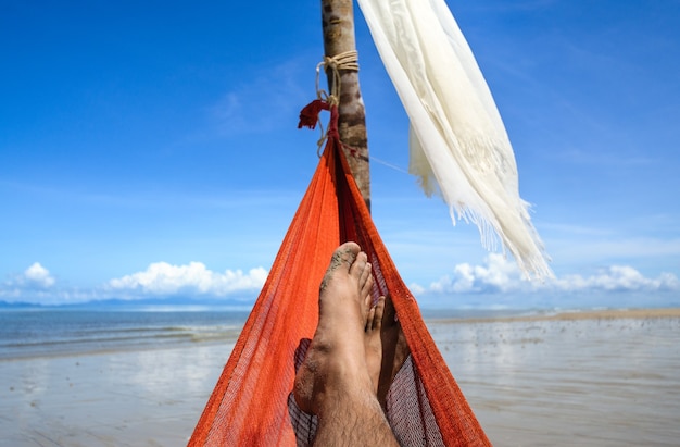 Ocio en verano, relajarse en una hamaca en la playa de arena, mirar al cielo.