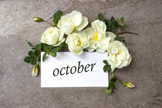 Octubre. Mes, mes calendario Borde de rosas blancas sobre fondo gris pastel con fecha del calendario. Otoño, concepto de mes del año.