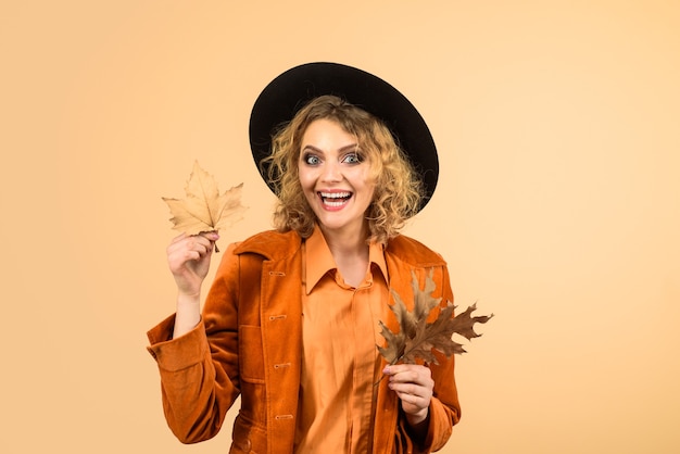 Octubre otoño niña con sombrero negro mujer otoño moda otoño mujer feliz con hojas de otoño en naranja