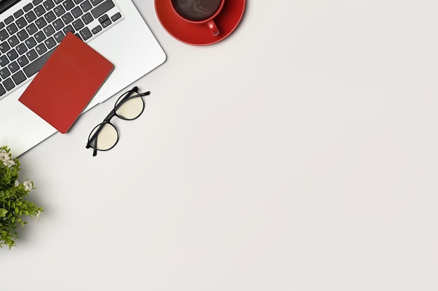 Óculos de computador portátil e xícara de café na mesa branca