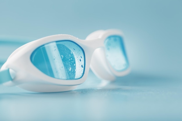 Óculos de natação em uma moldura branca com fundo azul