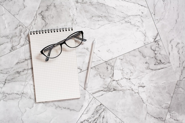 Óculos de notebook e uma caneta em uma telha de mármore pausa no trabalho design de casa escandinava