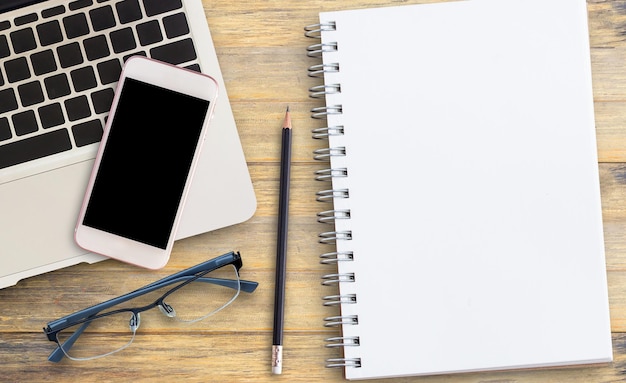 Foto Óculos de notebook em branco inteligente e computador portátil na mesa de escritório ou mesa de madeira