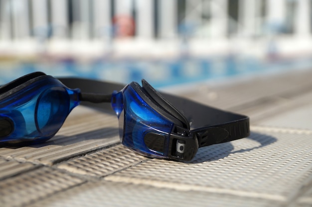 Óculos de proteção azuis para nadar na lateral da piscina