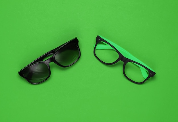 Óculos elegantes sem lentes e óculos de sol sobre fundo verde Vista superior