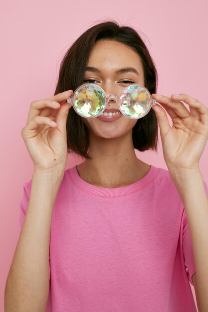 Óculos morenos de cabelos curtos em forma de diamantes em um fundo isolado de camiseta rosa