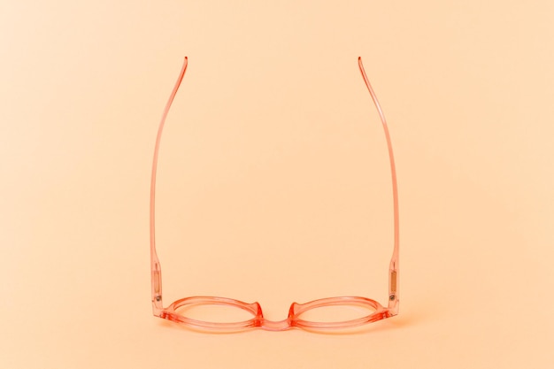 Foto Óculos transparentes rosa isolados em fundo bege