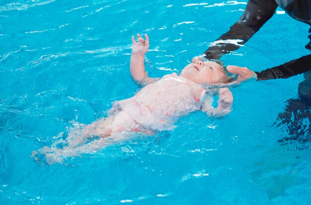 Ocupación en la piscina de niños con un entrenador de natación.