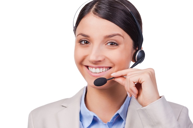 Ocupada en su trabajo. Seguro de servicio al cliente joven sonriendo mientras está de pie contra el fondo blanco.