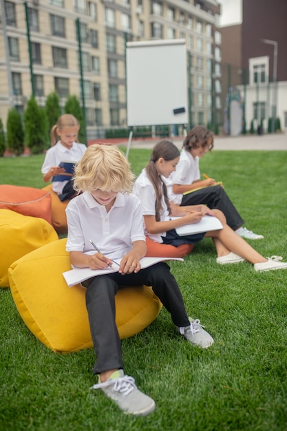 Ocupado. Grupo de alunos dando aula ao ar livre e parecendo concentrados