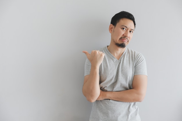 Odeie a cara do homem no t-shirt cinzento com ponto da mão no espaço vazio.