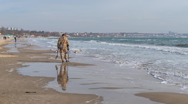 Odessa Ucrânia 07022022 Um homem procura objetos de valor usando detector de metais na praia Luzanivka em Odessa Ucrânia em um dia ensolarado de inverno
