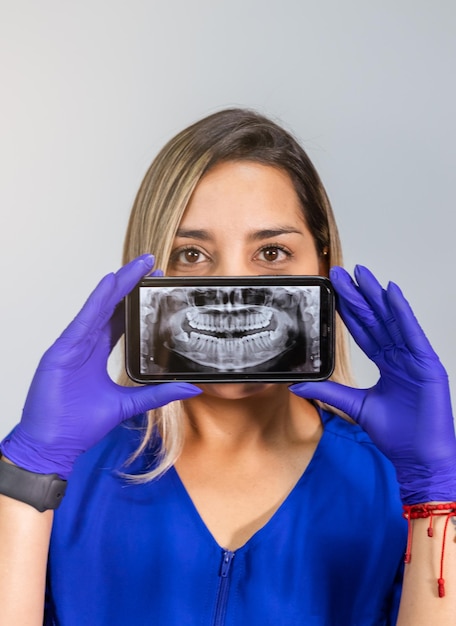 Odontologe hält Smartphone mit Panorama-Röntgenaufnahme des Mundes des Patienten