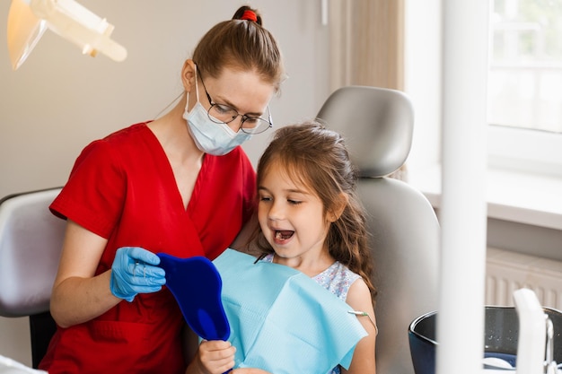 Odontología infantil Dentista y paciente infantil Consulta con dentista infantil en odontología Tratamiento de dientes Niño mirando en el espejo al dentista Paciente infantil feliz de odontología