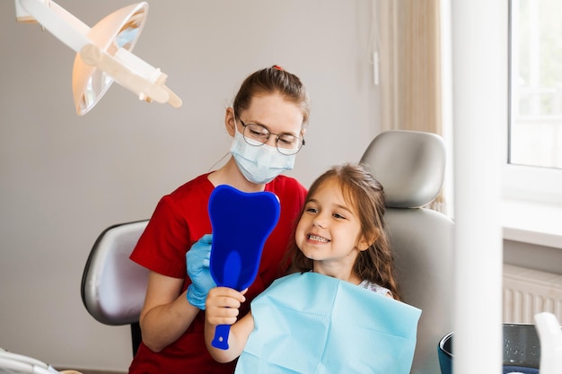 Odontología infantil Dentista y paciente infantil Consulta con dentista infantil en odontología Tratamiento de dientes Niño mirando en el espejo al dentista Paciente infantil feliz de odontología