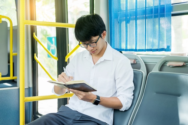 öffentlicher Verkehr, Mobilität. hübsches junges Geschäftsmannlesebuch auf Bus