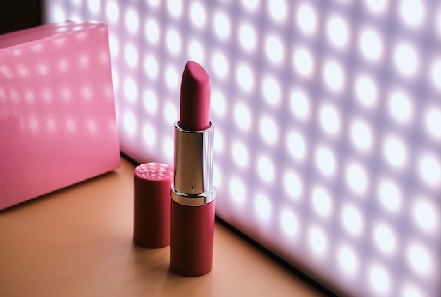 Öffnen Sie den rosa Lippenstift gegen die Oberfläche des LED-Lichts